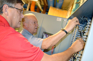 Recommissioning team members Drew Benfield (left) and Ray Lambert test a low-voltage control panel in Engineering Building I.