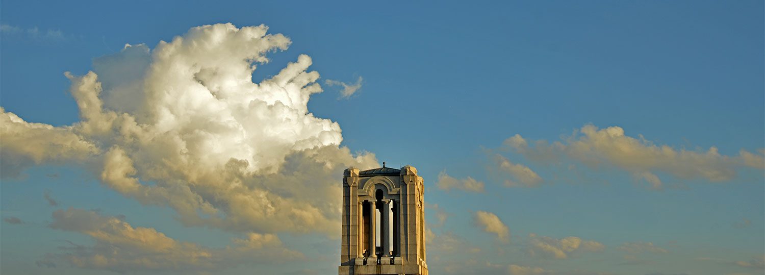 The memorial belltower stands tall against a blue sky and clouds