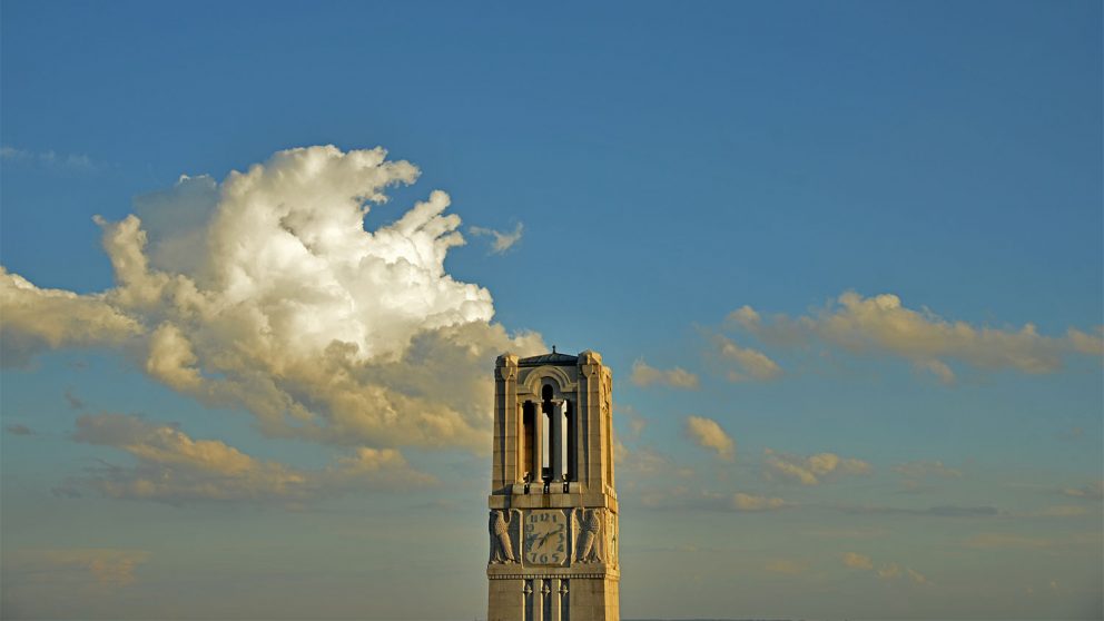 The memorial belltower stands tall against a blue sky and clouds