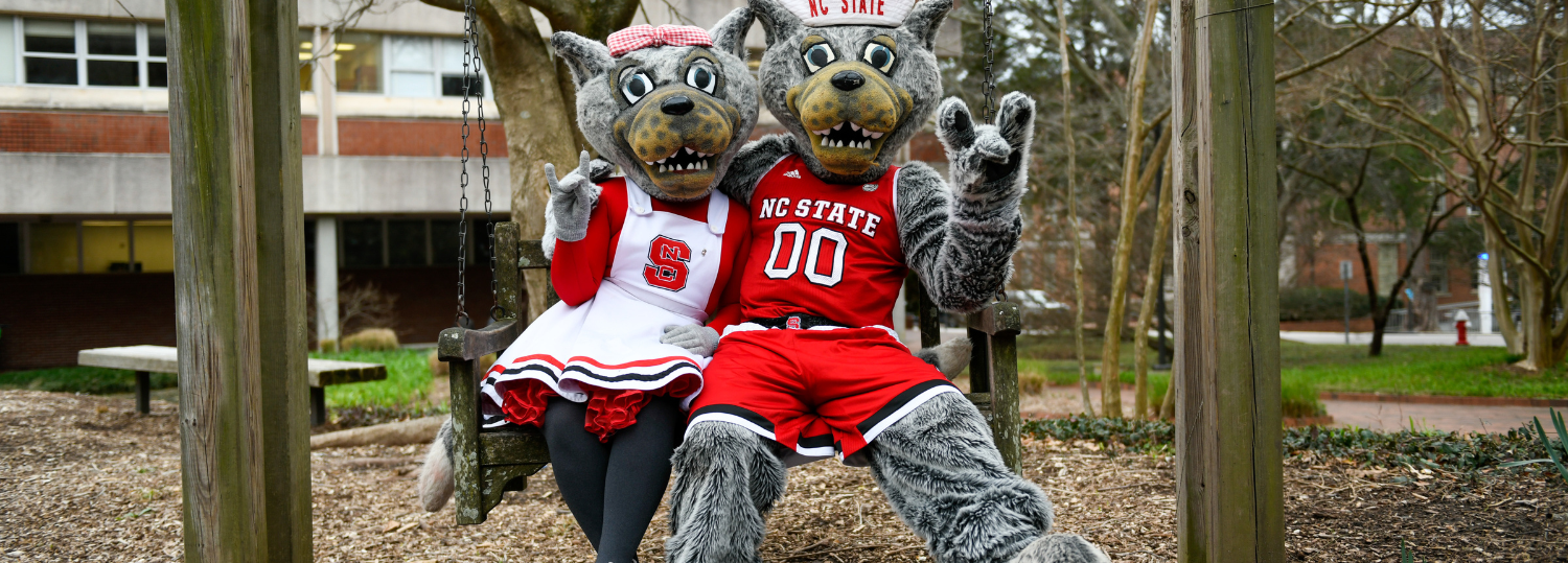 Ms Wuf and Mr Wuf sit together on a swing outside on campus