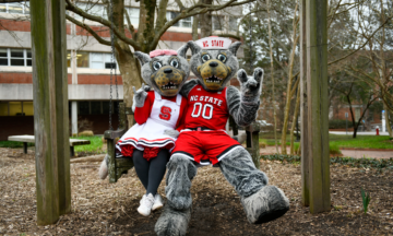 Ms Wuf and Mr Wuf sit together on a swing outside on campus