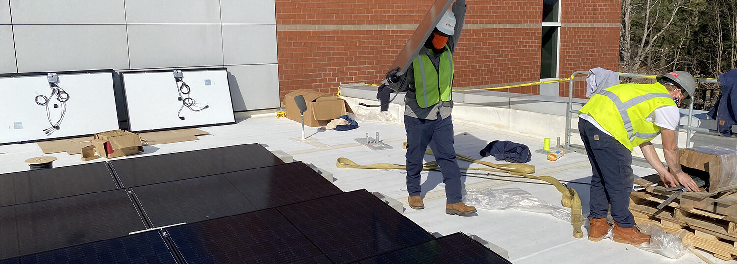 Worker carries solar panel on the roof of the Murphy Center.