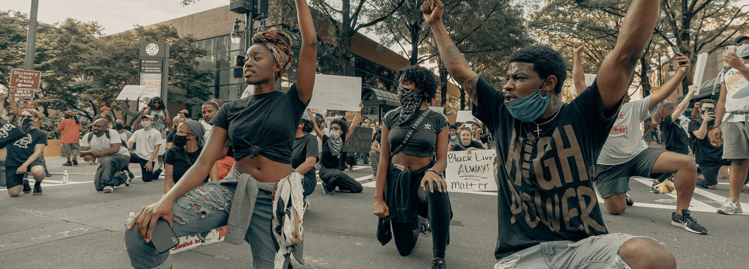 several Black young people kneel as part of a Black Lives Matter protest