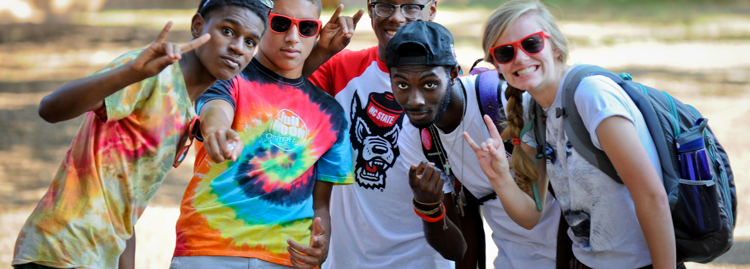 Group of students pose together making the Wolfpack sign.