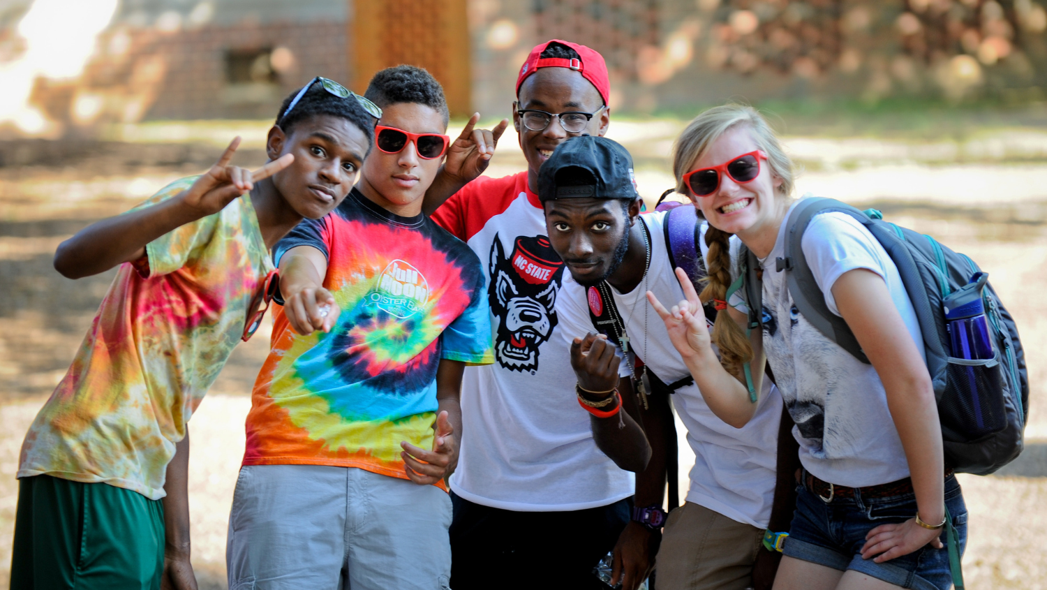 Group of students pose together making the Wolfpack sign.