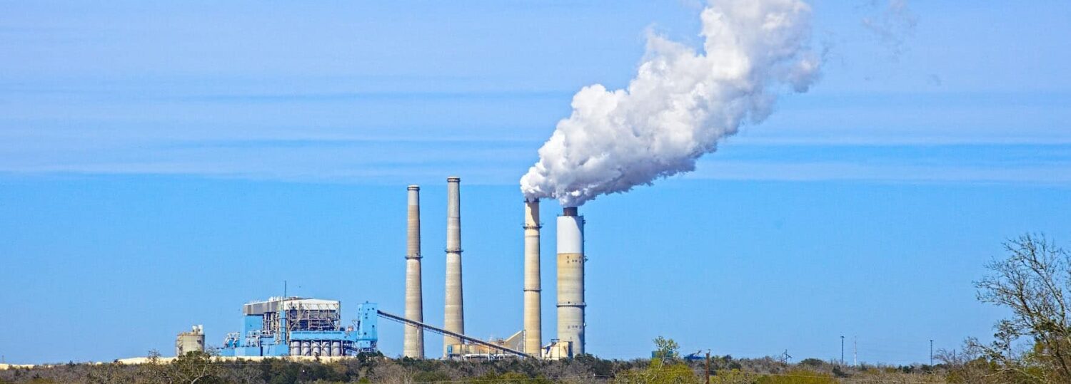 a coal-fired power plant in Texas releases a white cloud against a blue sky