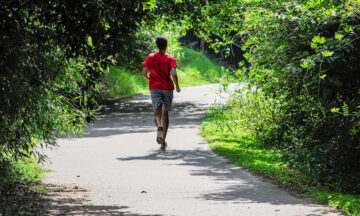 A jogger in a red shirt on a wooded trail