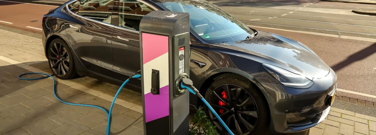 a sports car is parked on a city street and is plugged in to an electric vehicle charging station