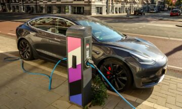 a sports car is parked on a city street and is plugged in to an electric vehicle charging station