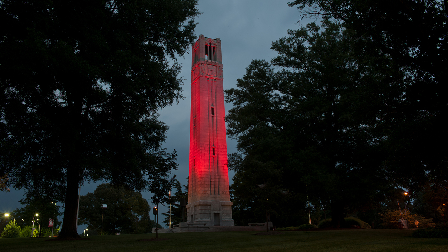 Looking up at the NC State belltower that is lit in red.