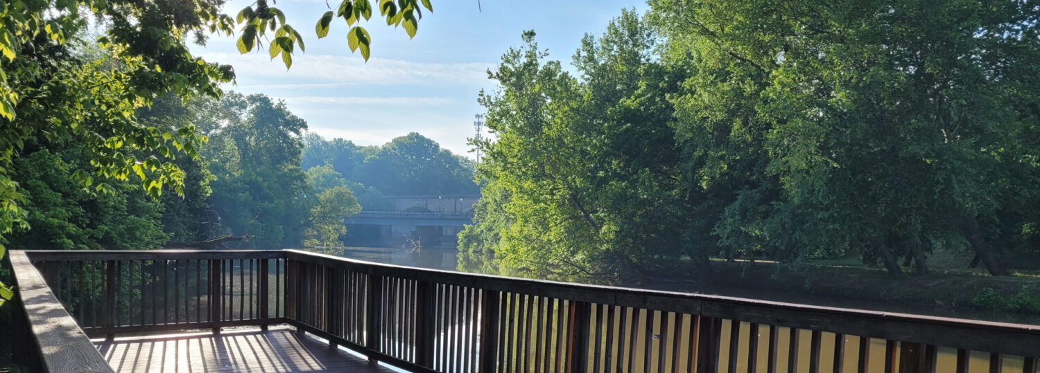 A scenic view from a wooden deck looking over a river on a sunny day