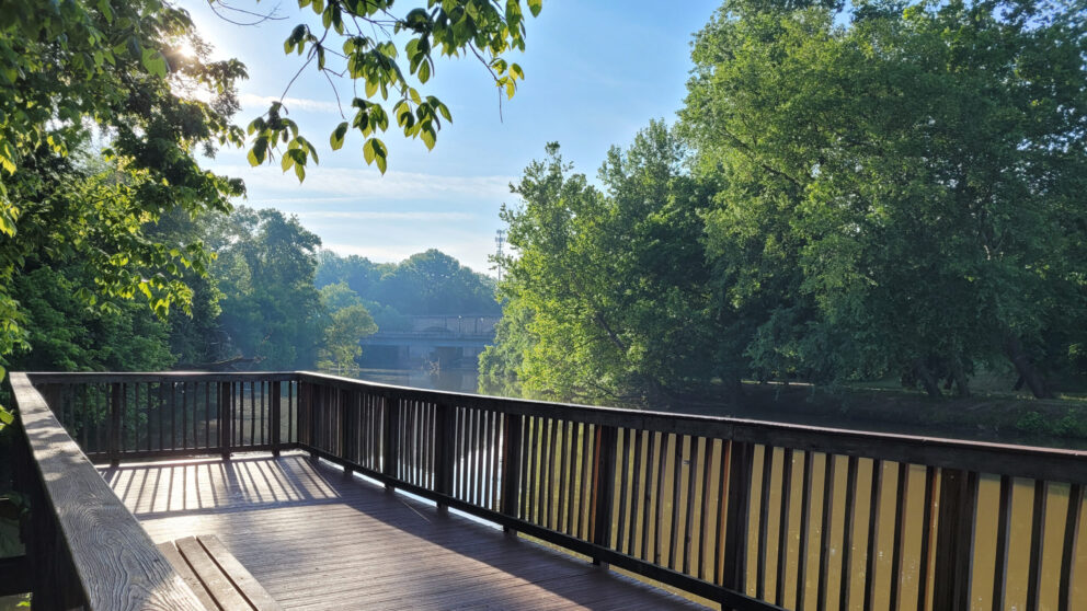 A scenic view from a wooden deck looking over a river on a sunny day