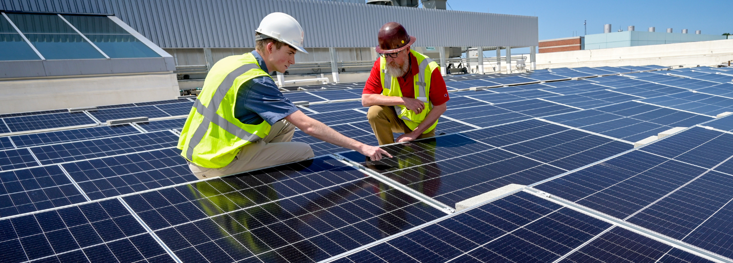 Student and staff examine solar array on top of Fitts-Woolard Hall wearing PPE