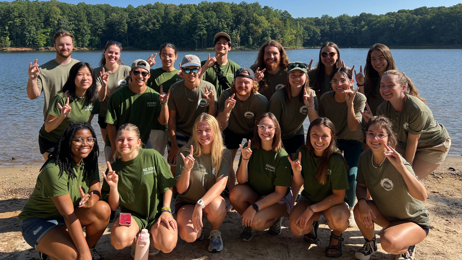 Group photo of Sustainability Stewards standing in front of lake wearing green t-shirts