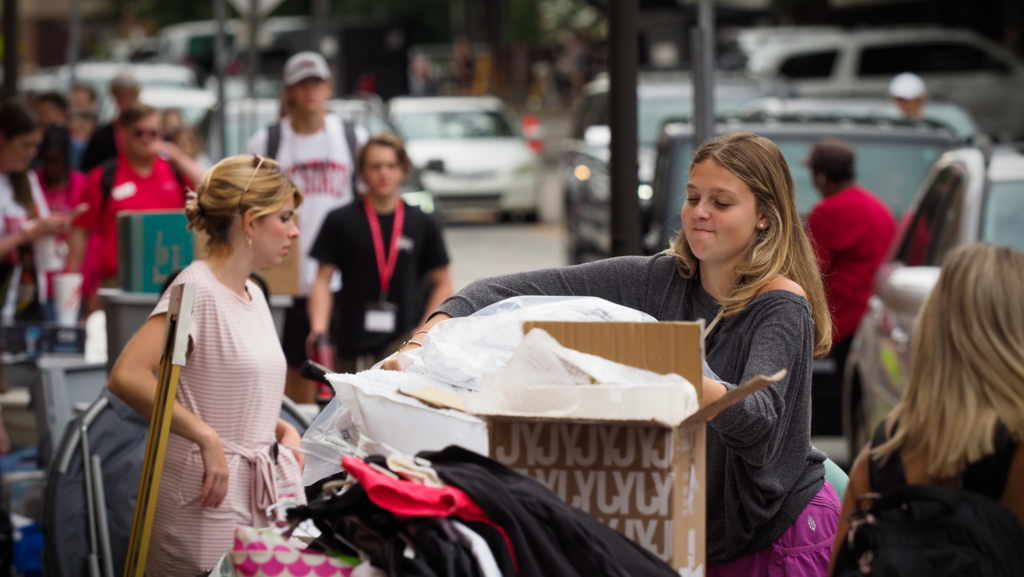 Move-in day on Cates Ave with students holding boxes and clothing and dorm items