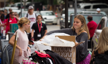 Move-in day on Cates Ave with students holding boxes and clothing and dorm items