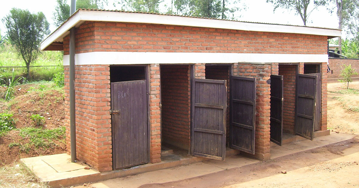 a small brick building with five wooden doors that open directly into a tidy, dirt courtyard.