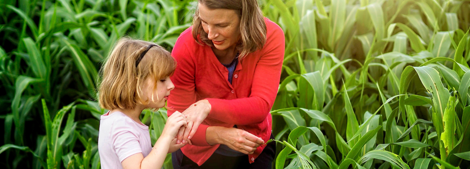 Professor and Extension specialst in Entomology and plant pathology, Hannah Burrack and a young child examine a small bug they found in a corn field at the Lake Wheeler farm. Photo by Marc Hall