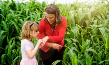 Professor and Extension specialst in Entomology and plant pathology, Hannah Burrack and a young child examine a small bug they found in a corn field at the Lake Wheeler farm. Photo by Marc Hall