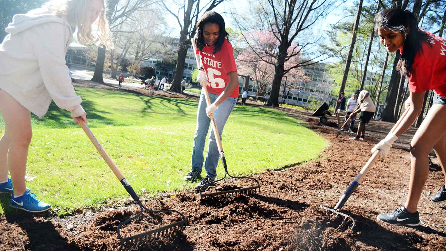 3 students til dirt on campus as part of volunteer project