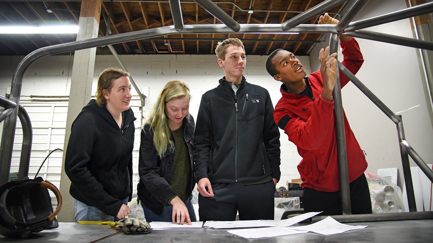 Mechanical engineering's Bryon Spells (right) points out recent welding work to SolarPack teammates while checking on the progress of their car at Eastern Rod and Customs.