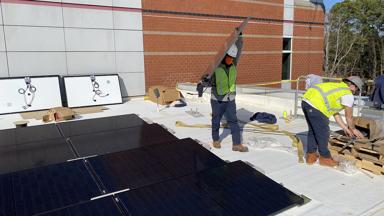 Worker carries solar panel on the roof of the Murphy Center.