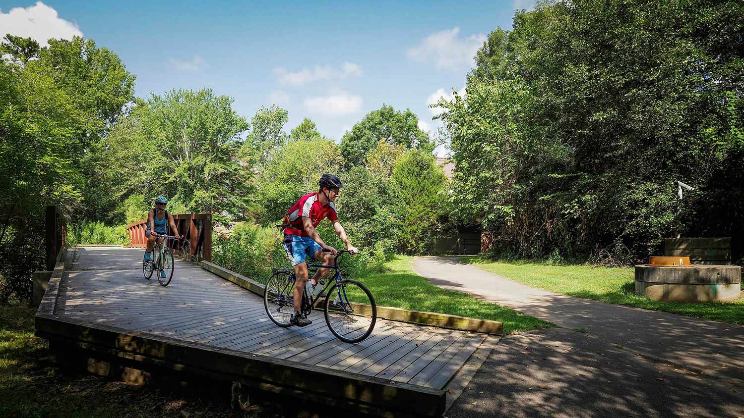 Man and women bike on boardwalk at the park.