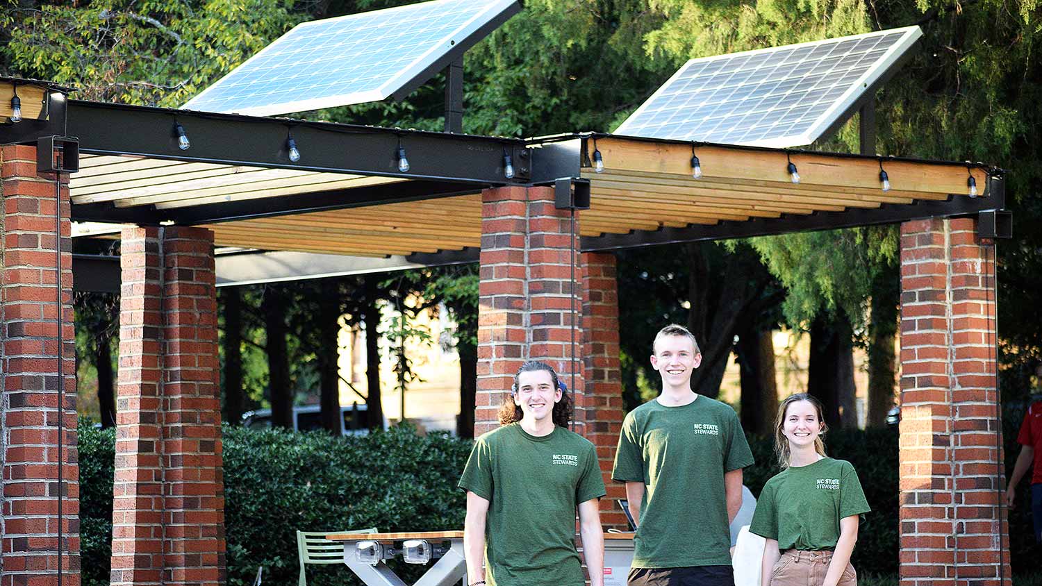 NC State Stewards (left to right) Benjamin Helms, Elias Zauscher and Alie Akins at SolarSpace, a new outdoor study space powered by renewable energy.