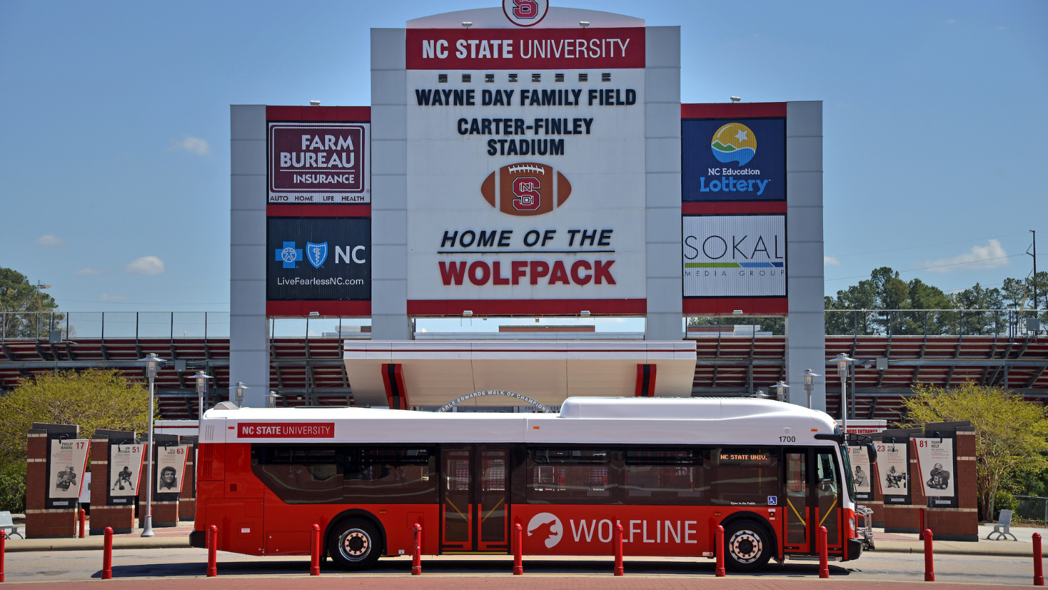 A Wolfline bus is parked in front of the Wayne Day Family Field, Carter Finley Stadium.