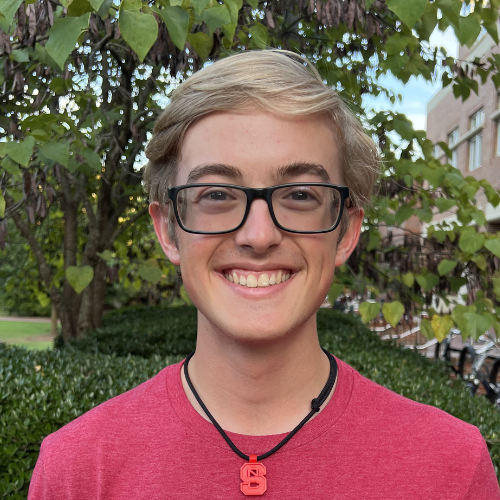 Headshot of Sustainability Steward Trey Mumma wearing a red shirt and NC State necklace.