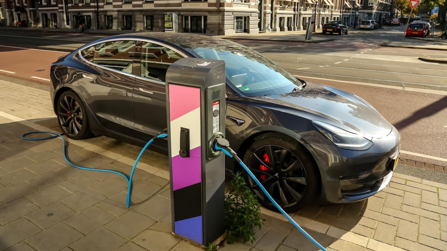 a sports car is parked on a city street and is plugged in to an electric vehicle charging station