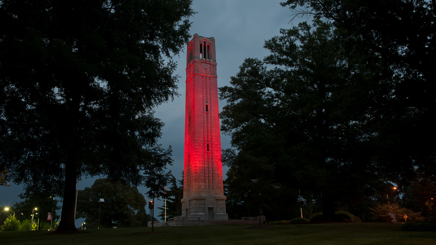 Looking up at the NC State belltower that is lit in red.