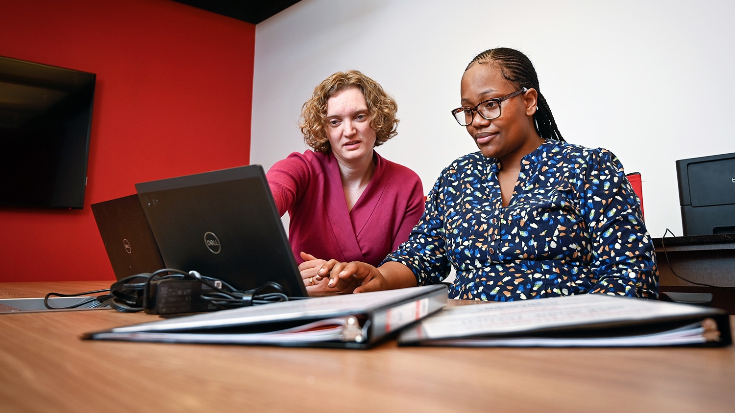 Two staff members sit together working on their computers.