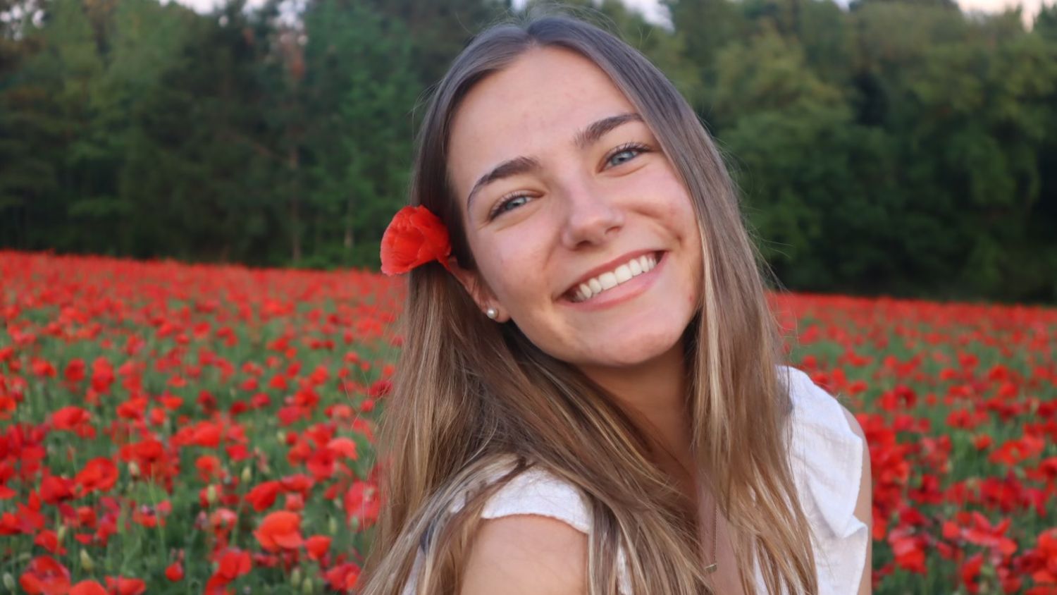 Sarah Grace Stone smiles in front of flowers.