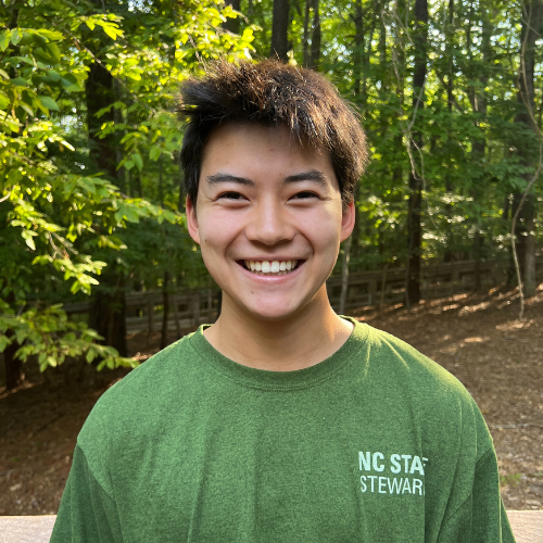 Headshot of Sustainability Stewards Brayden Rorick wearing green tshirt outside in front of treeline