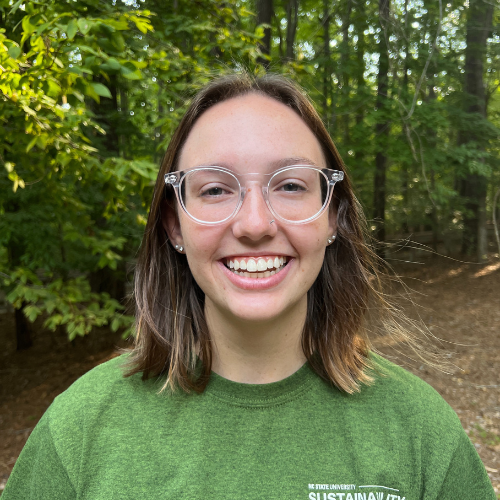 Headshot of Sustainability Stewards Brooke Parrinello wearing green tshirt outside in front of treeline