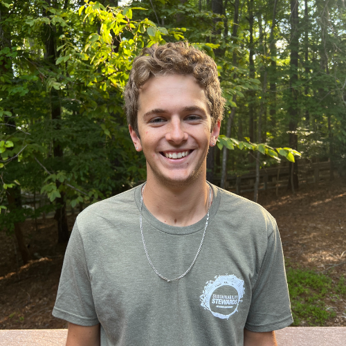 Headshot of Sustainability Stewards Jack Voight wearing green tshirt outside in front of treeline