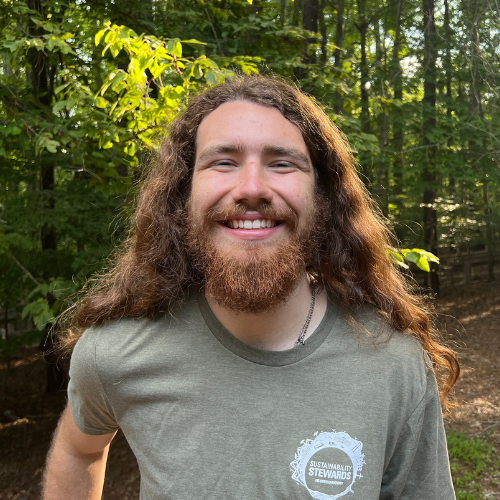 Headshot of Sustainability Stewards Jam Hill wearing green tshirt outside in front of treeline