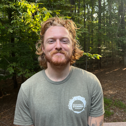 Headshot of Sustainability Stewards Jules Mainor wearing green tshirt outside in front of treeline