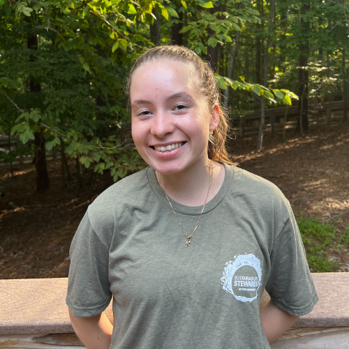 Headshot of Sustainability Stewards Julia Antipova wearing green tshirt outside in front of treeline