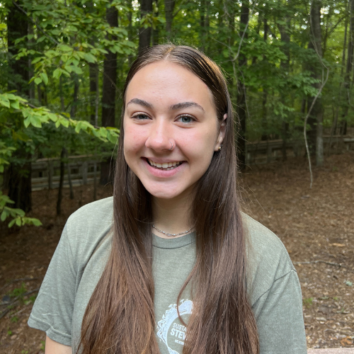 Headshot of Sustainability Stewards Madison Chema wearing green tshirt outside in front of treeline