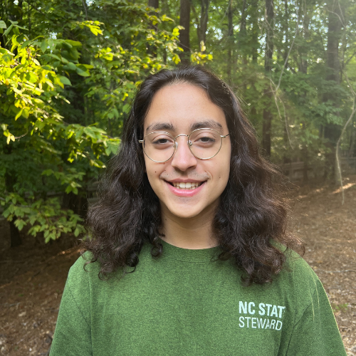 Headshot of Sustainability Stewards Patrick Cordona Cosner wearing green tshirt outside in front of treeline