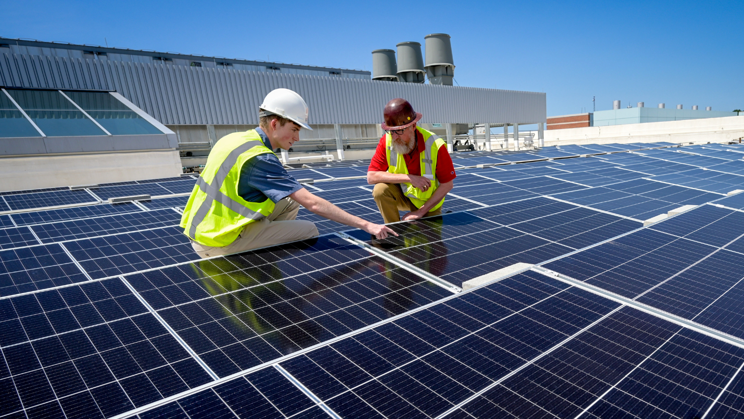 Student and staff examine solar array on top of Fitts-Woolard Hall wearing PPE