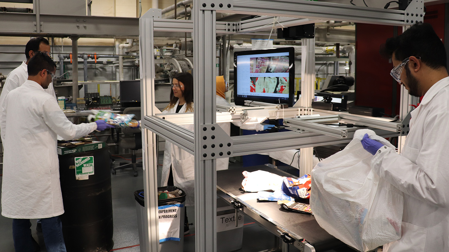 NC State researchers place waste items on a conveyor belt.