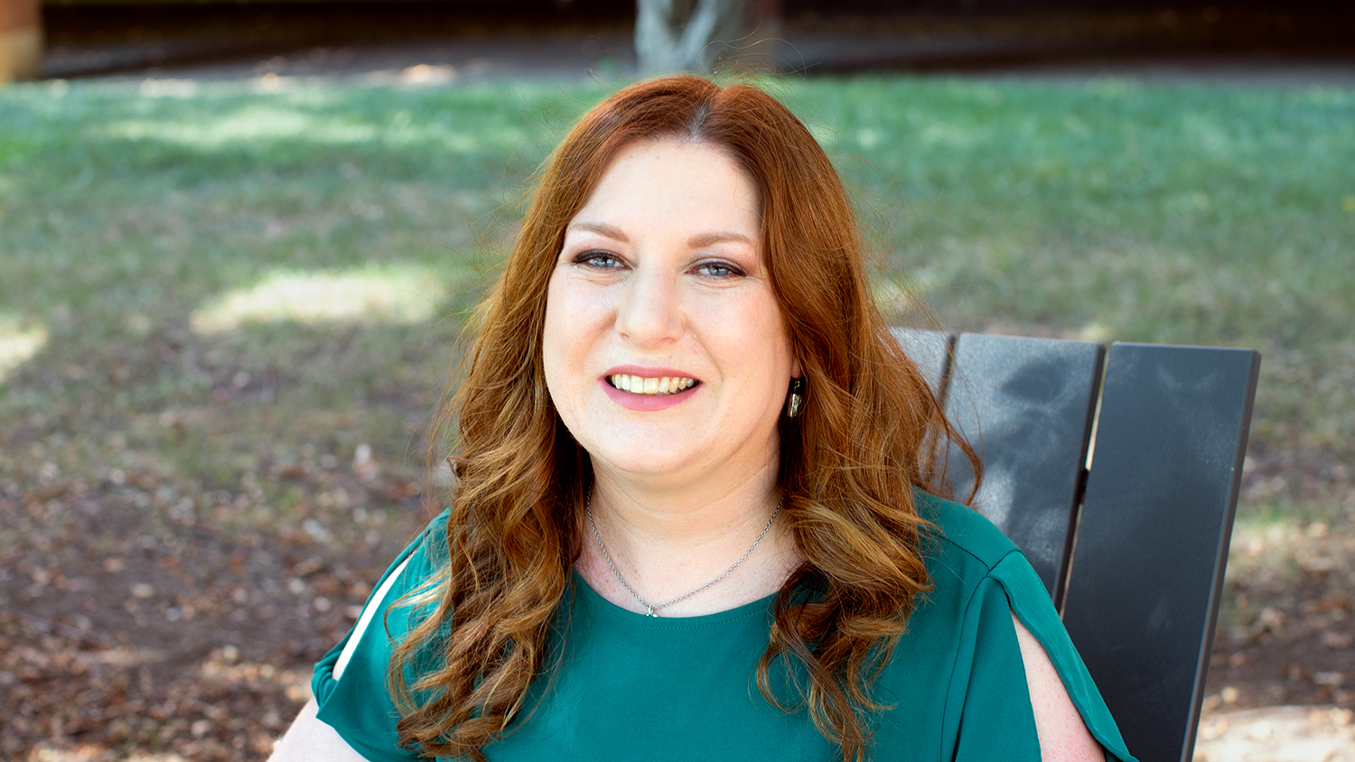 headshot of Megan Lupek, assistant teaching professor at NC State, sitting in a chair outside