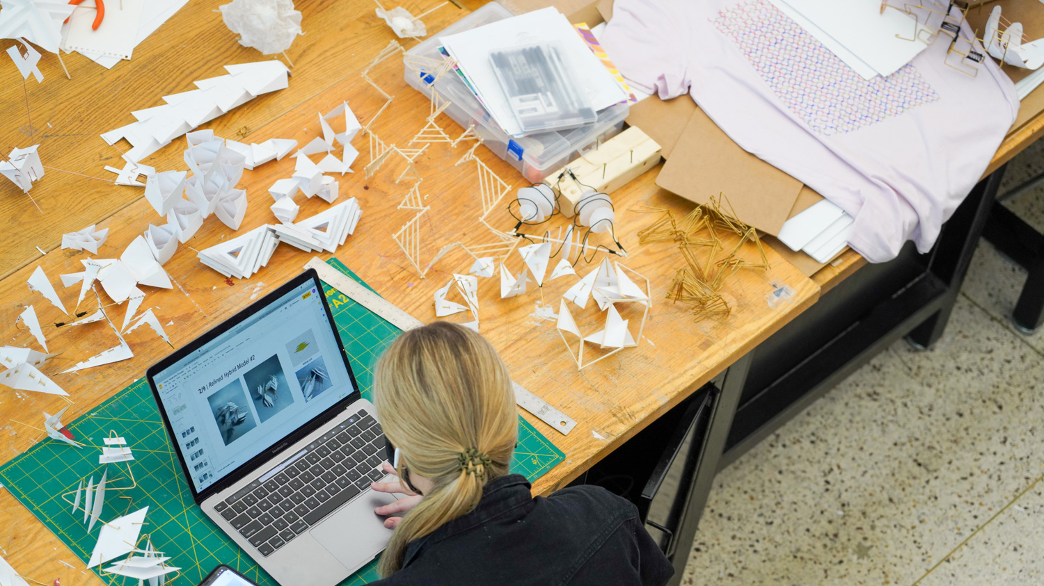 Student in studio with paper projects.