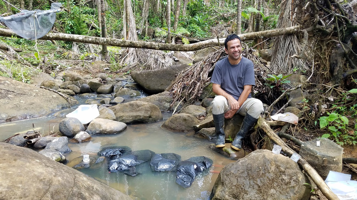 a man sits by a rocky stream bed