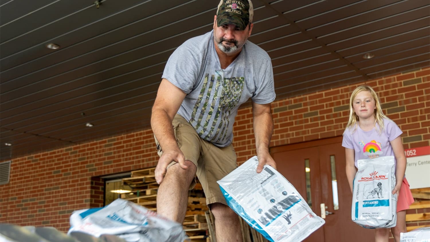 A man and a young girl load bags of pet food onto a truck to take to western North Carolina as part of the Hurricane Helene relief effort