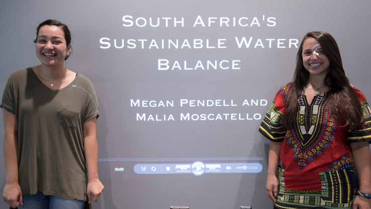 2 student winners stand in front of screen